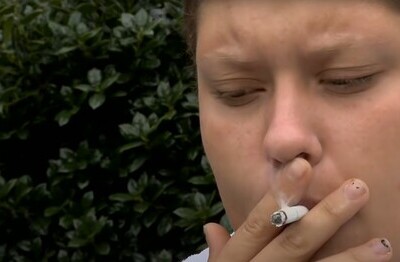 Человек с сигаретой делает затяжку